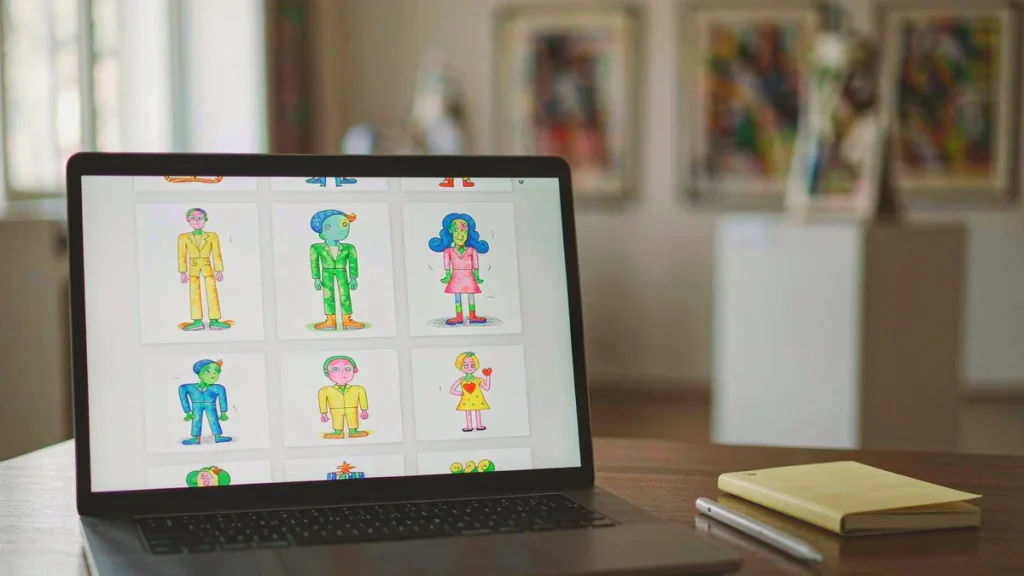 Laptop displaying a grid of digital illustrations on a wooden desk